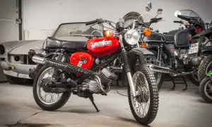 Czerwony Simson S51 Enduro, z widocznymi danymi technicznymi na baku. Obok inne motocykle i stary samochód.