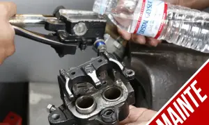 Ręce montują zacisk hamulcowy motocykla, przygotowując go do momentu dokręcania jarzma zacisku. W tle widać zbiorniczek płynu hamulcowego.