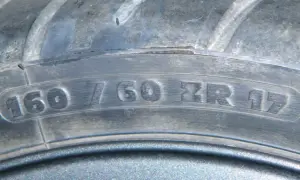 Zbliżenie na bieżnik opony z widocznym oznaczeniem 160/60 ZR 17.