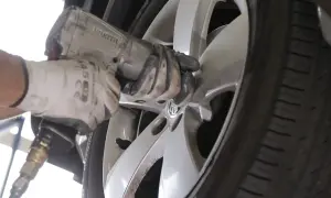 Mechanik w białej rękawicy dokręca śruby w feldze, zastanawiając się, ile km wytrzymują opony.