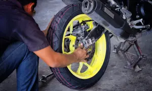 Mechanik pracuje przy motocyklu, wymieniając oponę. Profesjonalny serwis opon motocyklowych.