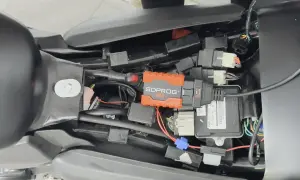 Pomarańczowe urządzenie SDPROG OBD podłączone do instalacji motocykla. Może to być przyczyną, że motocykl dławi się przy dodawaniu gazu.