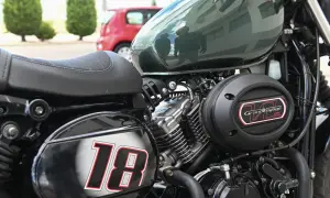 Część motocykla z siedzeniem, silnikiem i napisem "Grand Voyage 125". Numer "18" na błotniku.