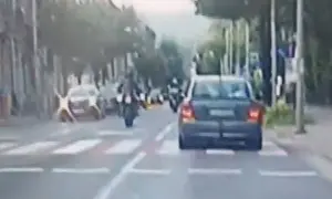 Motocyklista wykonuje jazdę na jednym kole, ryzykując mandat. Samochód jedzie przed nim.