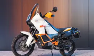 Pomarańczowo-biały motocykl enduro KTM 990 Adventure gotowy na przygodę.
