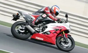 Motocyklista w czerwonym kombinezonie śmiga na torze Yamahą R6. Od ilu lat można robić prawo jazdy na motor 600? Od 20 lat na kategorię A.