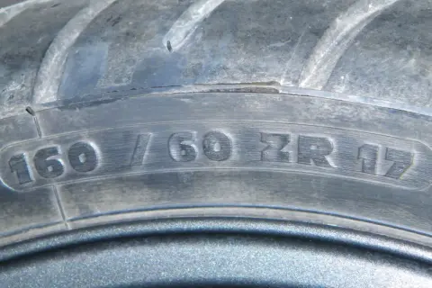 Zbliżenie na bieżnik opony z widocznym oznaczeniem 160/60 ZR 17.