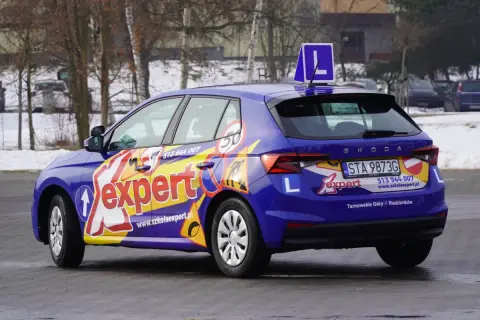 Niebieski samochód szkoleniowy z napisem "expert" i literą "L" na dachu. Zapytaj, ile trwa kurs na prawo jazdy kat A.
