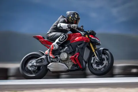 Motocyklista w kombinezonie pędzi na czerwonym Ducati Streetfighter V2, unosząc się lekko nad torem.