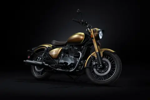 Złoty motocykl Royal Enfield z brązowym siedzeniem, prezentowany na czarnym tle. Klasyczny styl i moc.