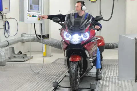Mechanik sprawdza motocykl na hamowni. Regularny przegląd motocykla 125 zapewnia jego sprawność.
