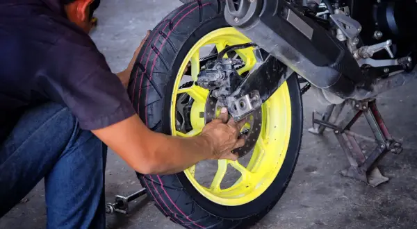 Mechanik pracuje przy motocyklu, wymieniając oponę. Profesjonalny serwis opon motocyklowych.