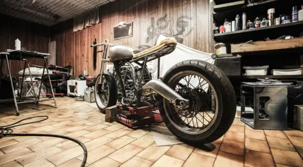 Warsztat z motocyklem na podnośniku. Widoczne **zawieszenie upside down** i narzędzia.