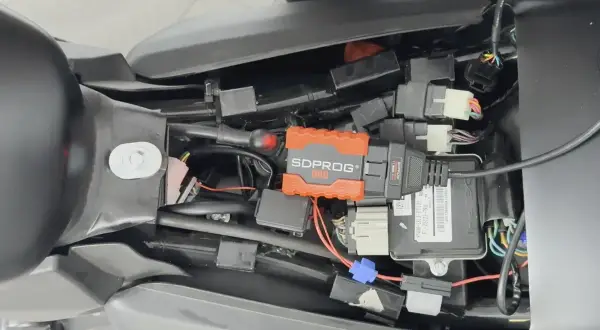 Pomarańczowe urządzenie SDPROG OBD podłączone do instalacji motocykla. Może to być przyczyną, że motocykl dławi się przy dodawaniu gazu.