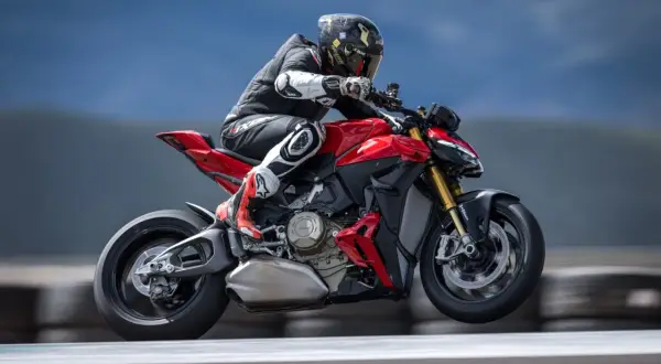 Motocyklista w kombinezonie pędzi na czerwonym Ducati Streetfighter V2, unosząc się lekko nad torem.