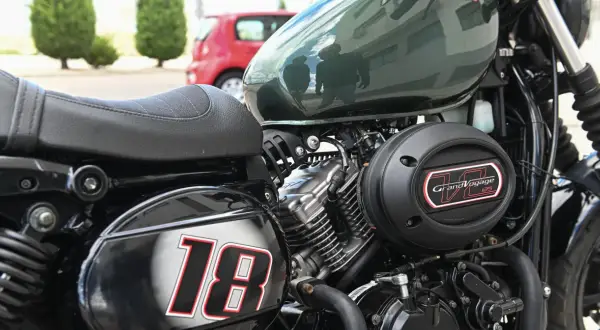 Część motocykla z siedzeniem, silnikiem i napisem "Grand Voyage 125". Numer "18" na błotniku.