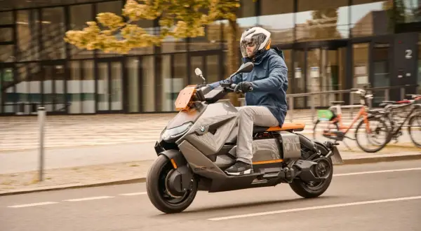 Mężczyzna w kasku jedzie na futurystycznym skuterze BMW CE04.