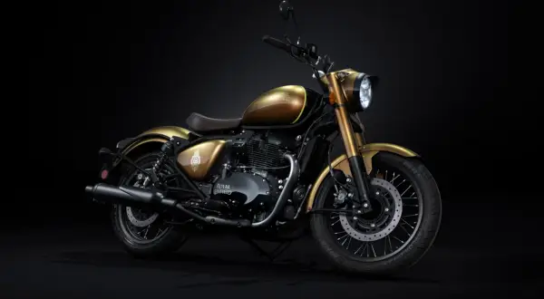 Złoty motocykl Royal Enfield z brązowym siedzeniem, prezentowany na czarnym tle. Klasyczny styl i moc.