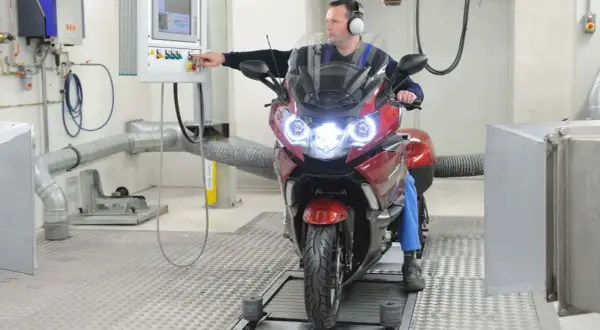 Mechanik sprawdza motocykl na hamowni. Regularny przegląd motocykla 125 zapewnia jego sprawność.