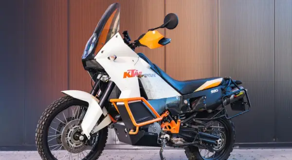 Pomarańczowo-biały motocykl enduro KTM 990 Adventure gotowy na przygodę.