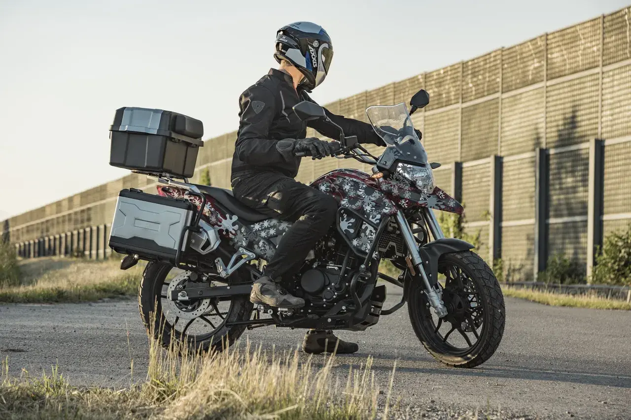 Motocyklista na Junak RX One 125 z kuframi, gotowy na zwiększenie mocy i przygodę.