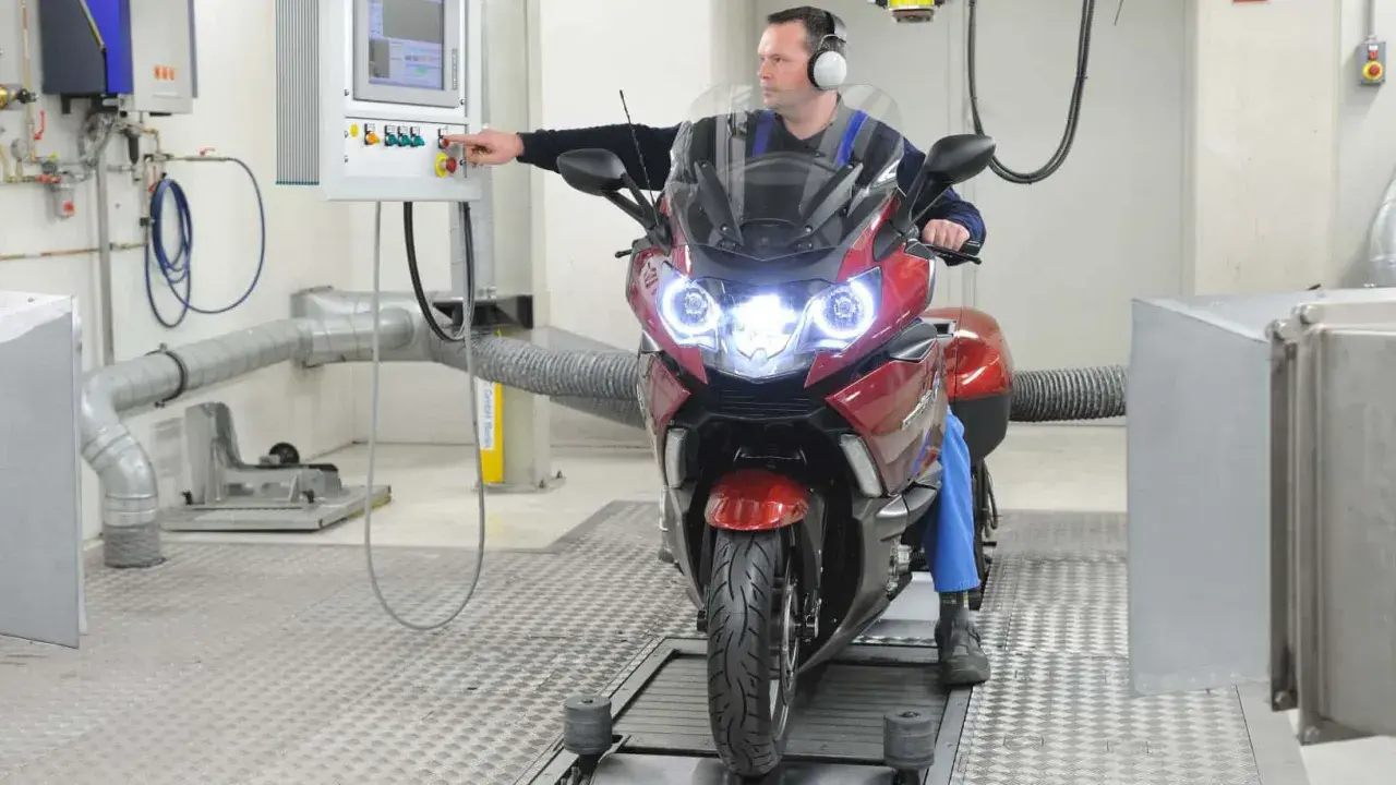 Mechanik sprawdza motocykl na hamowni. Regularny przegląd motocykla 125 zapewnia jego sprawność.