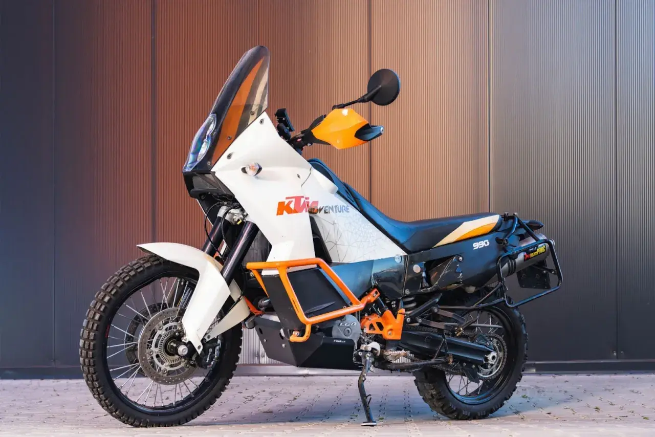 Pomarańczowo-biały motocykl enduro KTM 990 Adventure gotowy na przygodę.