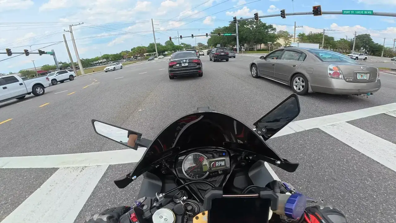 Widok z perspektywy motocyklisty. Motocykl dławi się przy dodawaniu gazu, stojąc w korku na skrzyżowaniu.