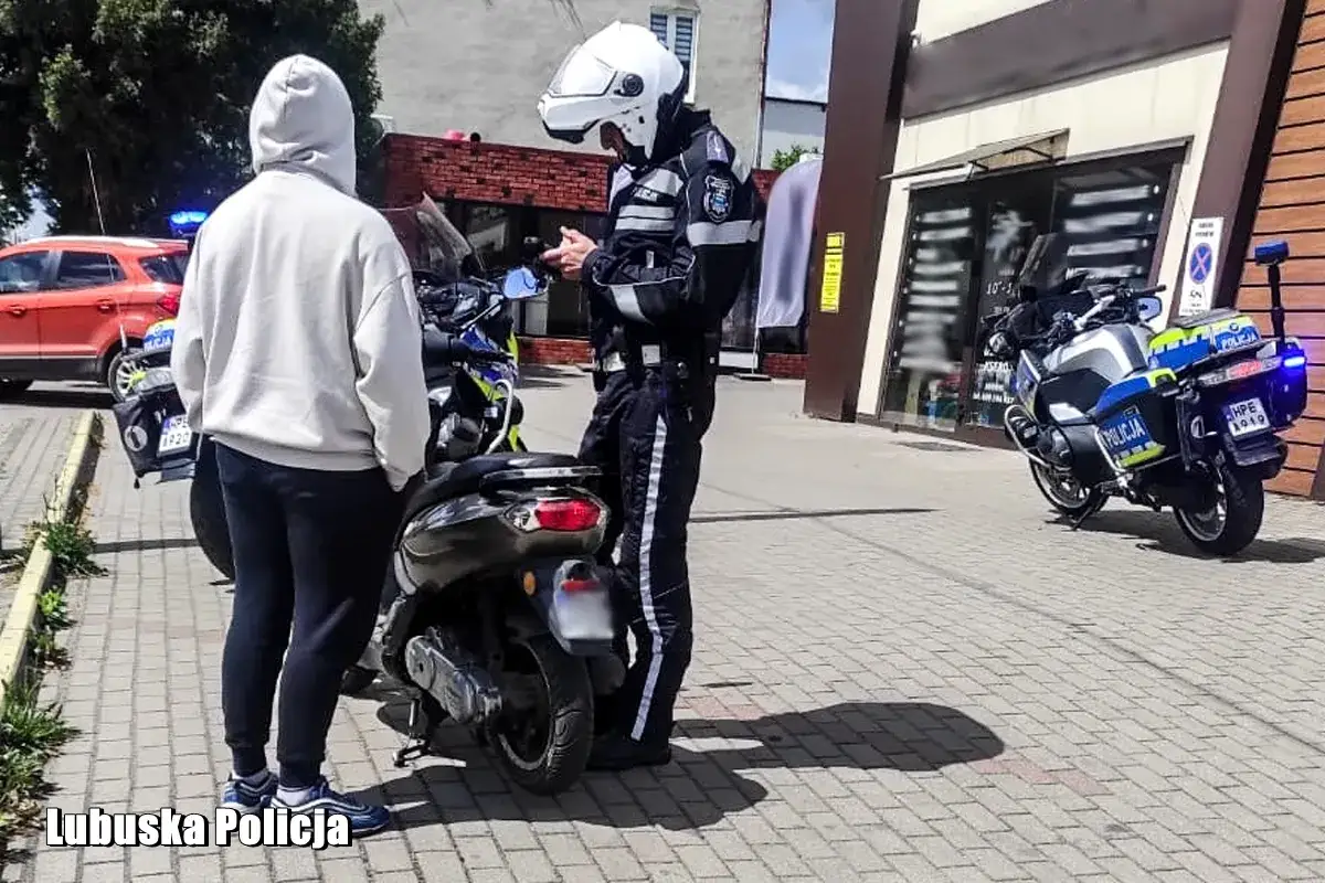 Policjant kontroluje dokumenty młodego mężczyzny przy skuterze. Dowiedz się, kto może jeździć skuterem na dow&oacute;d osobisty.