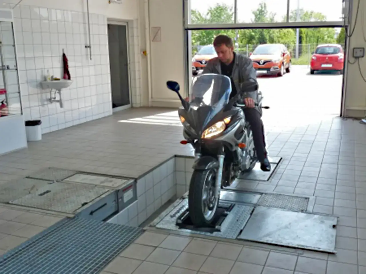 Mechanik na motocyklu 125 na stanowisku diagnostycznym. Sprawdza, co ile przegląd motocykla 125 jest zalecany.