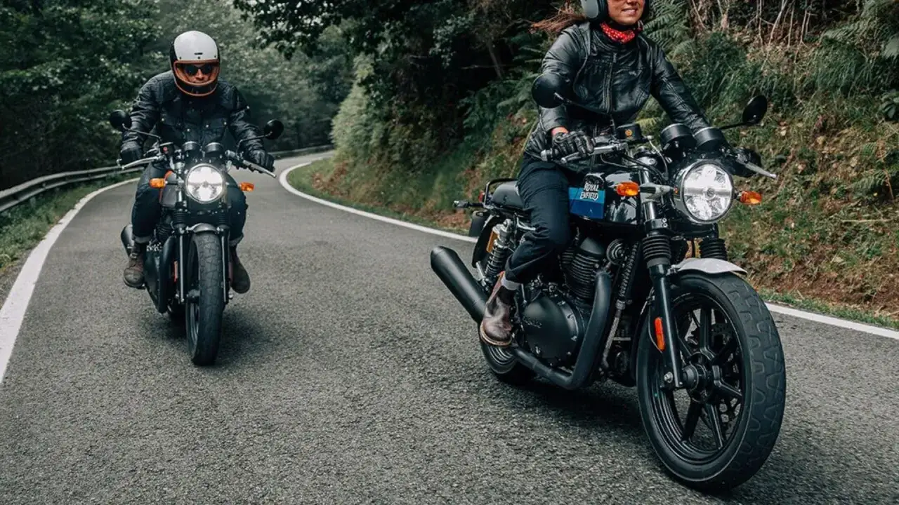 Dwie osoby na motocyklach Royal Enfield jadą krętą drogą wśr&oacute;d zieleni.