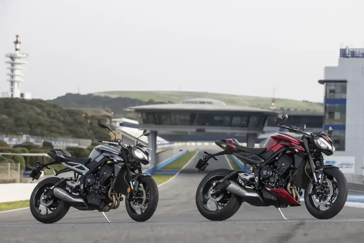 Dwa motocykle Triumph 675 Street Triple, jeden czarny, drugi czerwony, stoją na torze wyścigowym.