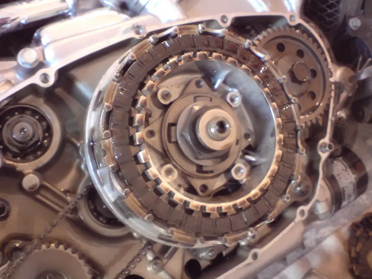 Widok mechanizmu sprzęgła motocyklowego z tarczami i zębatkami.