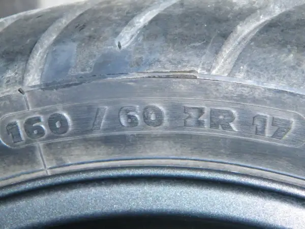 Zbliżenie na bieżnik opony z widocznym oznaczeniem 160/60 ZR 17.