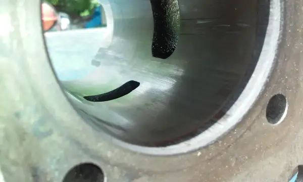 Wnętrze cylindra po docieraniu motocykla 125. Widać ślady honowania i fragmenty uszczelki.