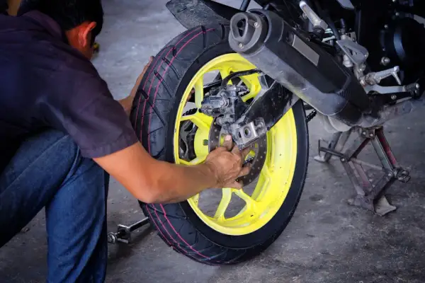 Mechanik pracuje przy motocyklu, wymieniając oponę. Profesjonalny serwis opon motocyklowych.