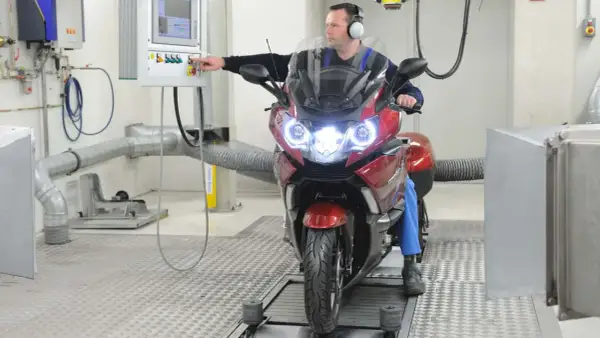 Mechanik sprawdza motocykl na hamowni. Regularny przegląd motocykla 125 zapewnia jego sprawność.